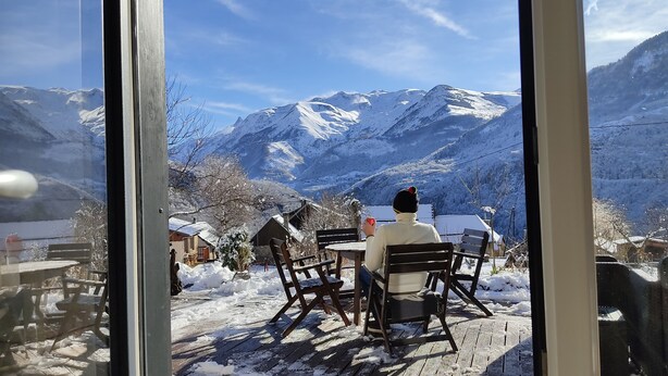 Une personne assise à une table, avec une vue sur la montagne.