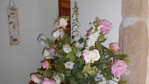 A floral arrangement in a vase on a stone ledge near a staircase. - Gîte 5 Personnes (Le Vast)