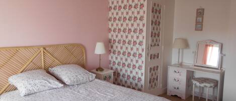 A bedroom with a bed, a nightstand, a dresser, a mirror, and a chair.