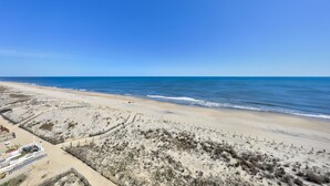 A beach with a clear sky, sandy dunes, and a fenced area with a building. - Summer Beach 801 by Seaside Vacations & Sales (Ocean City)