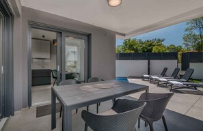 A patio area with a table and chairs, a pool, and a covered seating area.