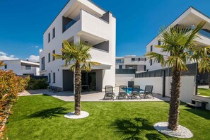 A modern two-story building with a flat roof, a swimming pool, and a well-maintained lawn.