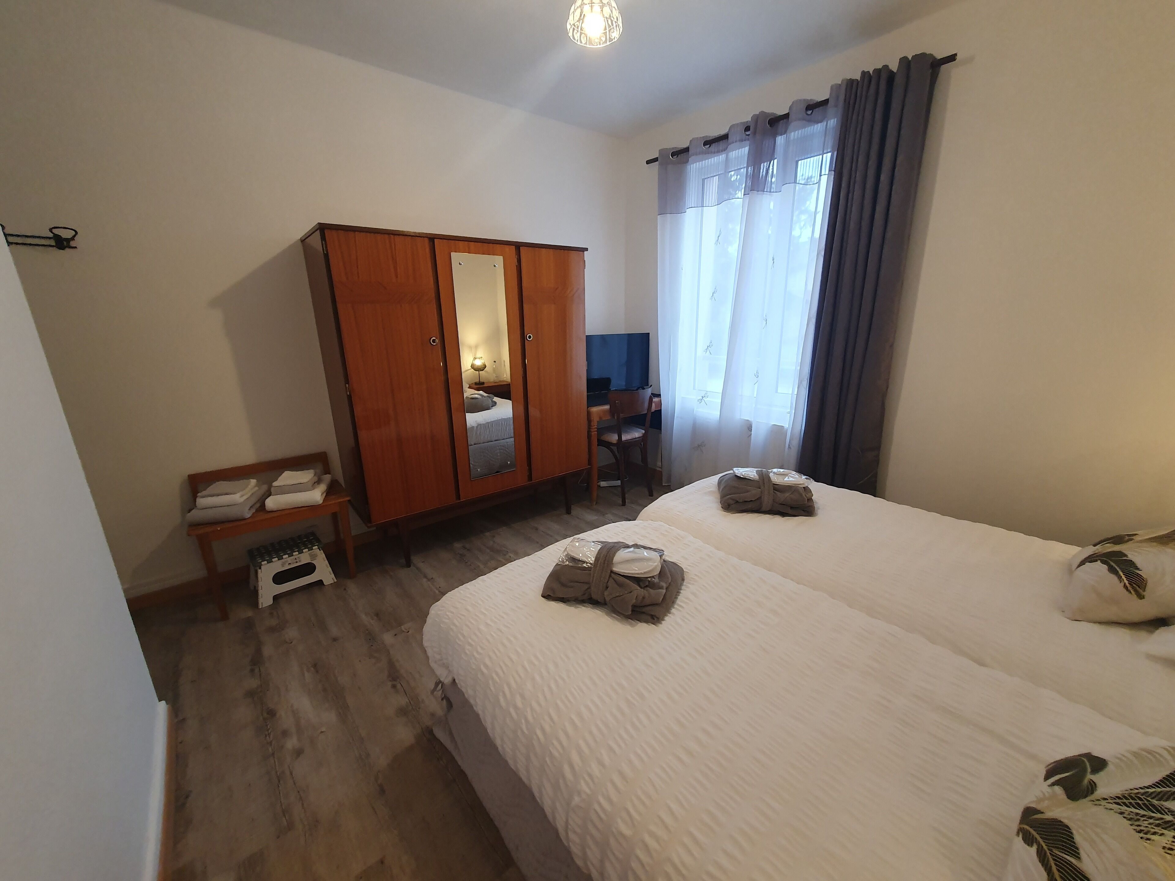 Ett hotellrum med två sängar, en garderob, ett skrivbord och en stol.