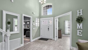 A spacious foyer with a wooden floor, white doors, and a staircase with a white railing.