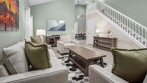 A living room with a sofa, coffee table, and a staircase leading to an upper floor.