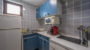Une cuisine avec des meubles bleus, un réfrigérateur blanc, un four à micro-ondes et une cuisinière.