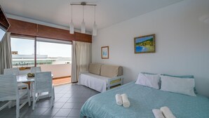 Une chambre d’hôtel comprenant un lit, un canapé, une table à manger avec des chaises et un balcon avec des rideaux.