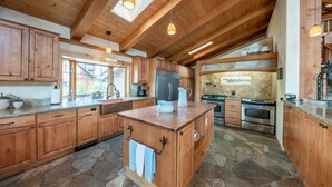 A spacious kitchen with wooden cabinets, a central island, and a stone floor.