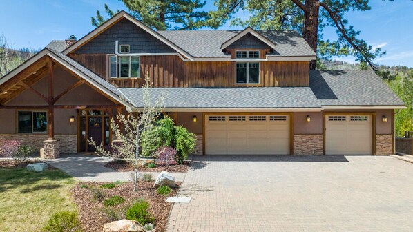 A two-story house with a stone foundation, a garage, and a landscaped driveway.