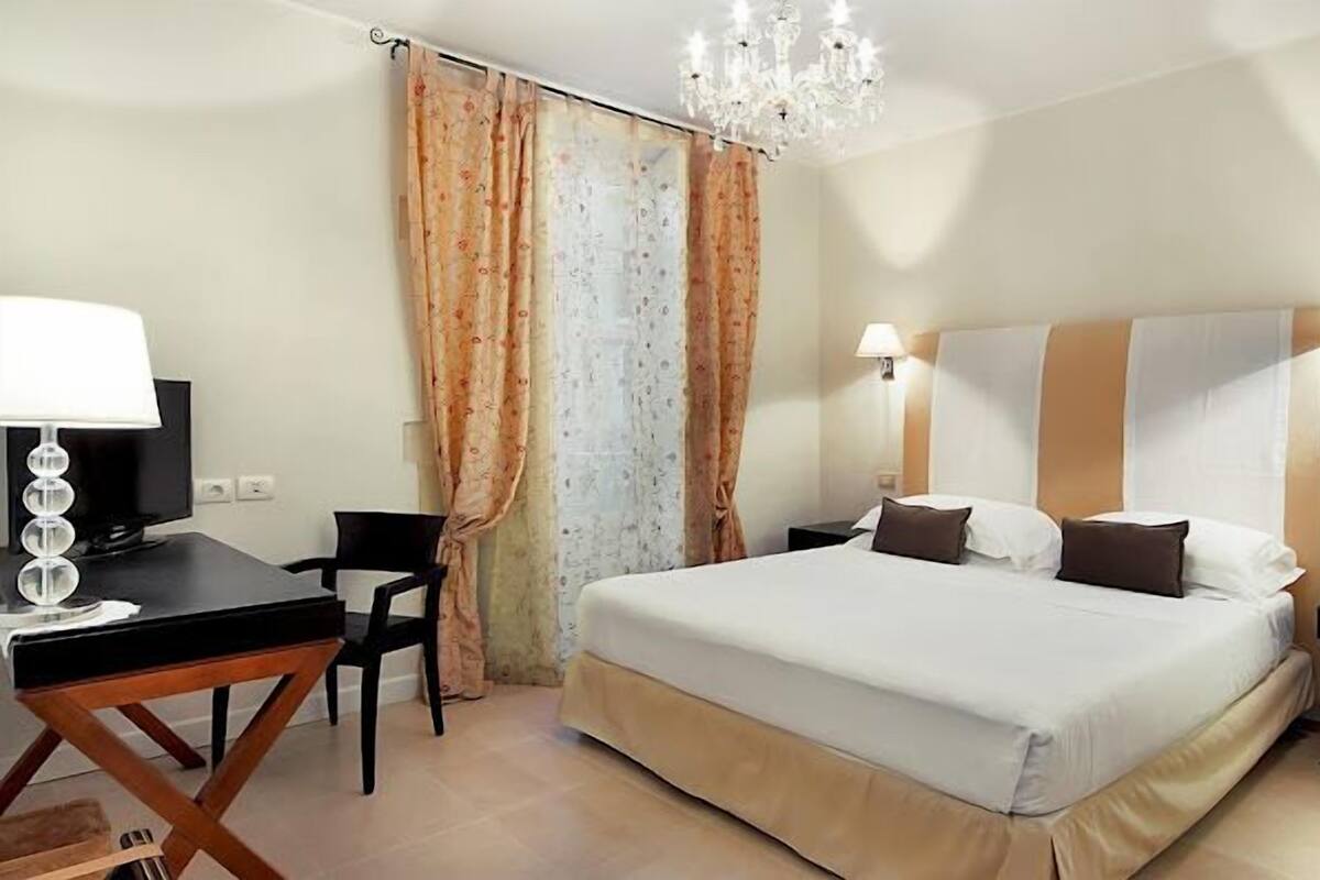 Une chambre d’hôtel comprenant un lit, un bureau avec une lampe, une chaise et un téléviseur.