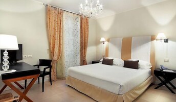 Une chambre d’hôtel comprenant un lit, un bureau avec une lampe, une chaise et un téléviseur.
