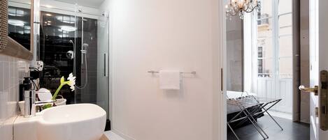 A modern bathroom with a large white bathtub, a glass shower enclosure, and a wooden vanity.