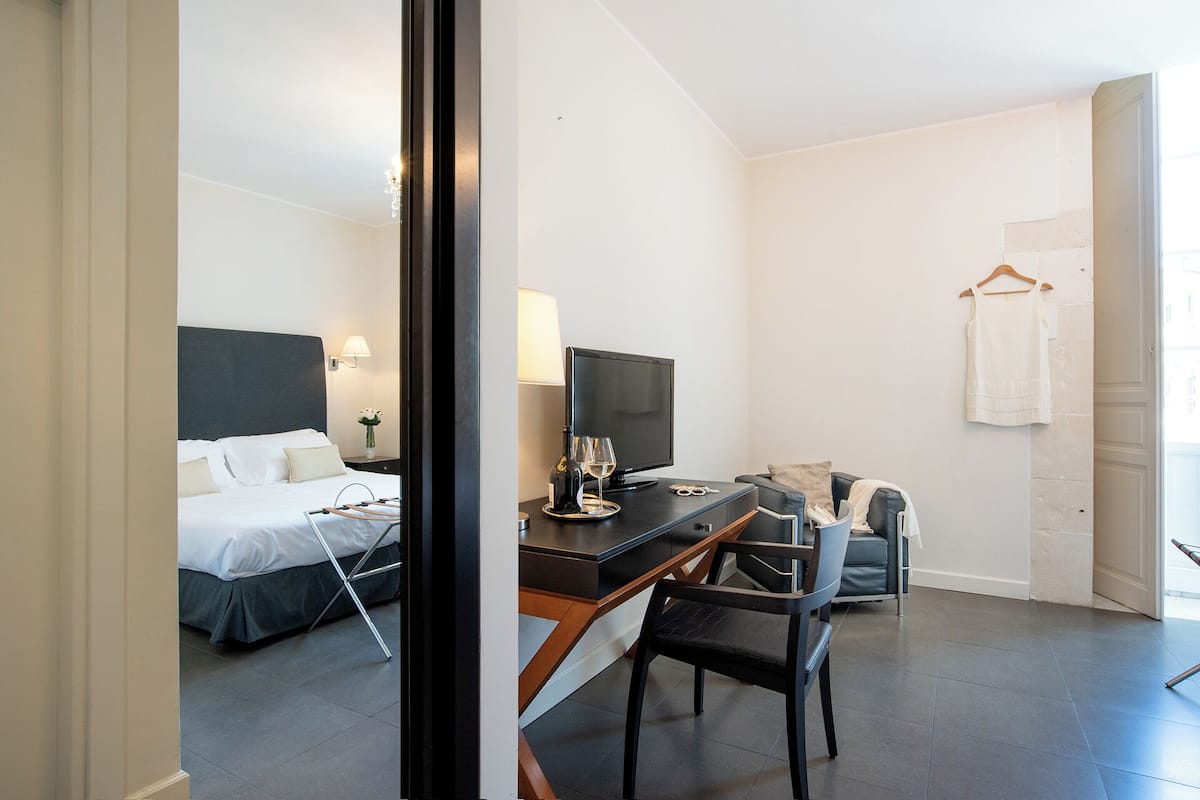 Une chambre d’hôtel comprenant un lit, un bureau avec une chaise, une télévision et une serviette suspendue.