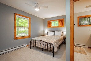 Quarto com cama, ventilador de teto, janela com persianas e aquecedor.