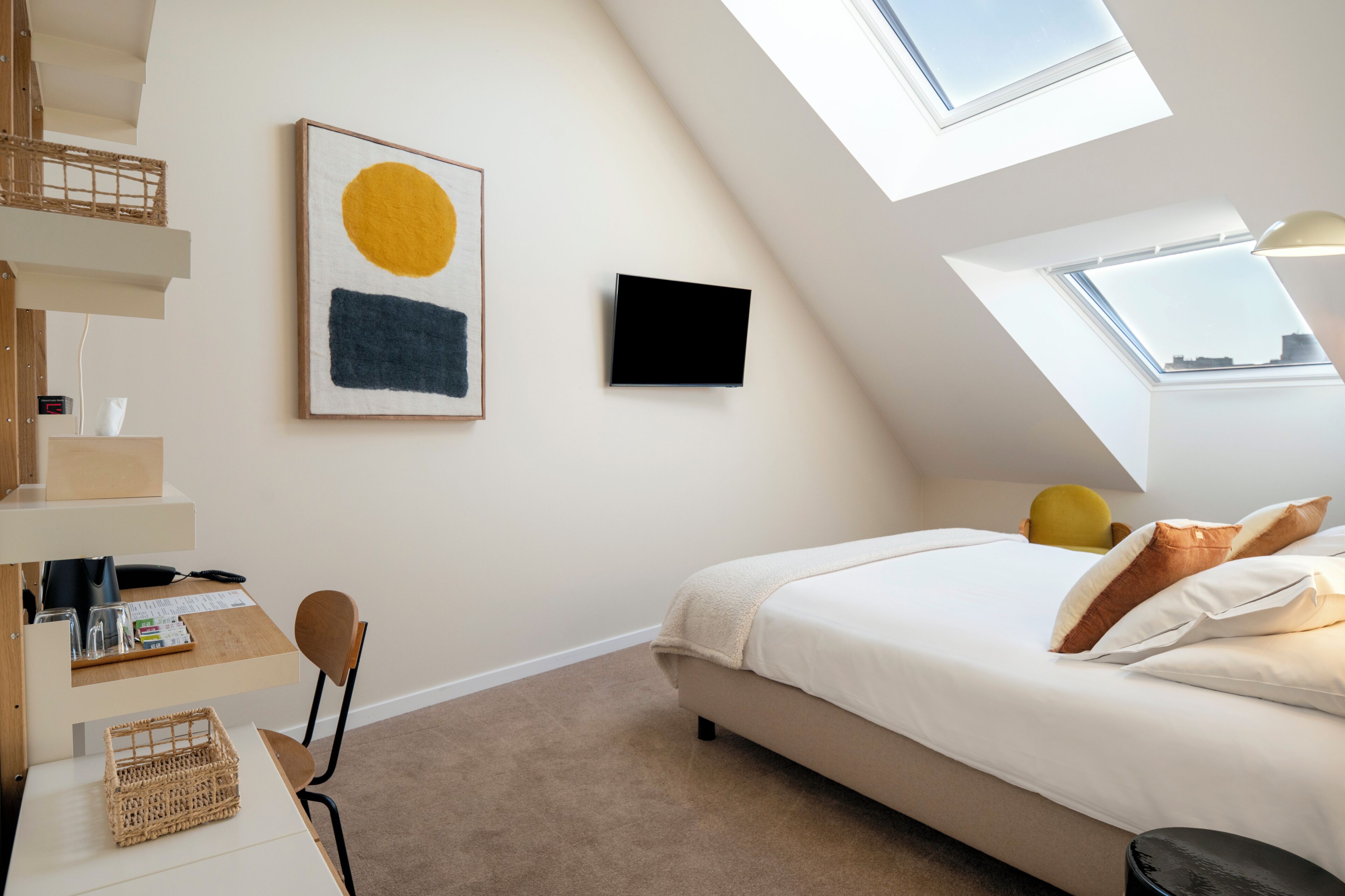 Ein Schlafzimmer mit Bett, Schreibtisch, Stuhl, Fernseher und einem Oberlicht.