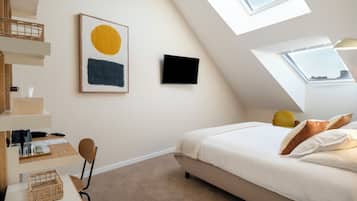 Ein Schlafzimmer mit Bett, Schreibtisch, Stuhl, Fernseher und einem Oberlicht.