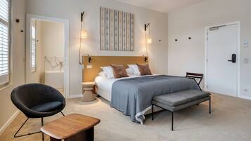 A modern bedroom with a bed, bedside tables, a chair, and a bench.