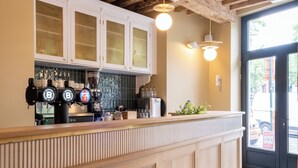 A bar area with a wooden counter, a coffee machine, and a glass display case. - Made in Catherine (Brussels)