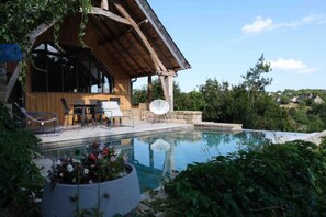 Una cabaña de madera con piscina, mobiliario de exterior y jardín.