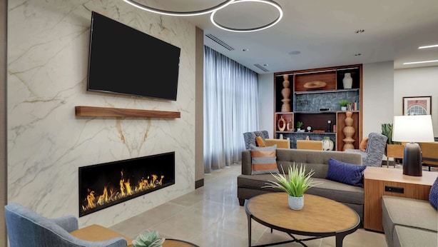 Una sala de estar moderna con televisor de pantalla plana, chimenea, un conjunto de sofás, una mesa de centro y una estantería.