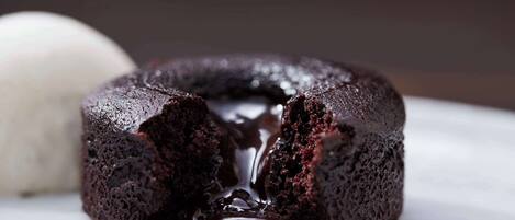 A chocolate lava cake with a gooey center and a scoop of vanilla ice cream beside it.