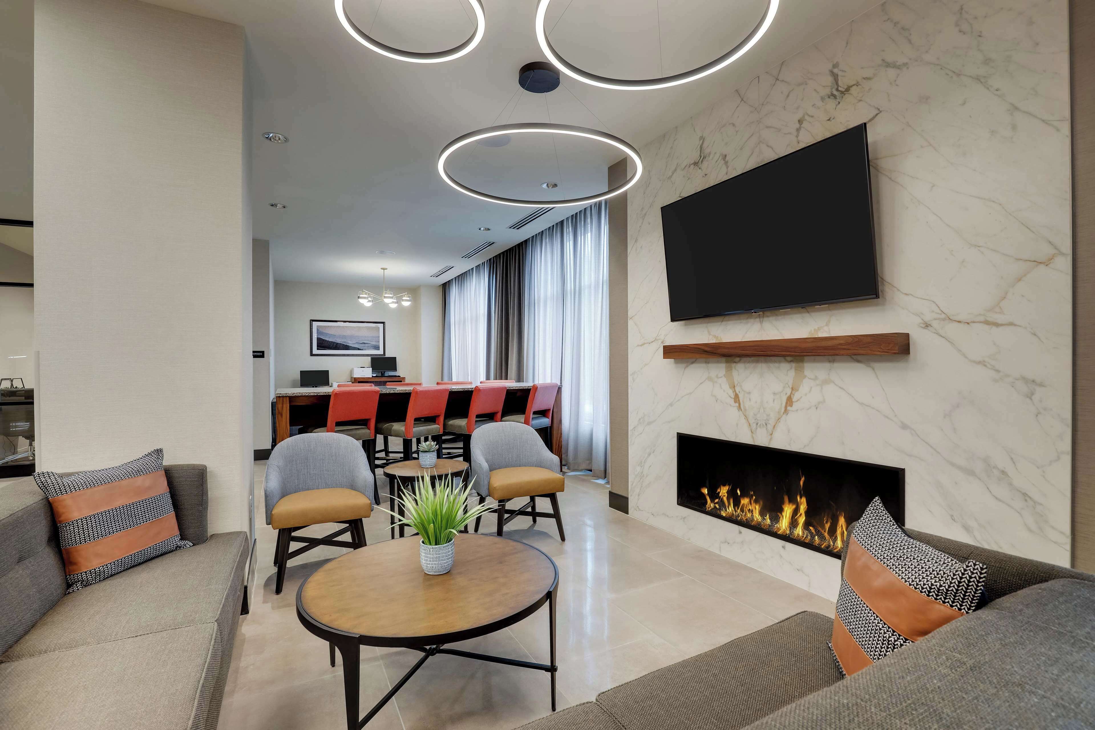 A modern living room with a fireplace, a dining area, and a TV mounted on the wall.