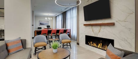 Una sala de estar moderna con chimenea, comedor y televisor en la pared.