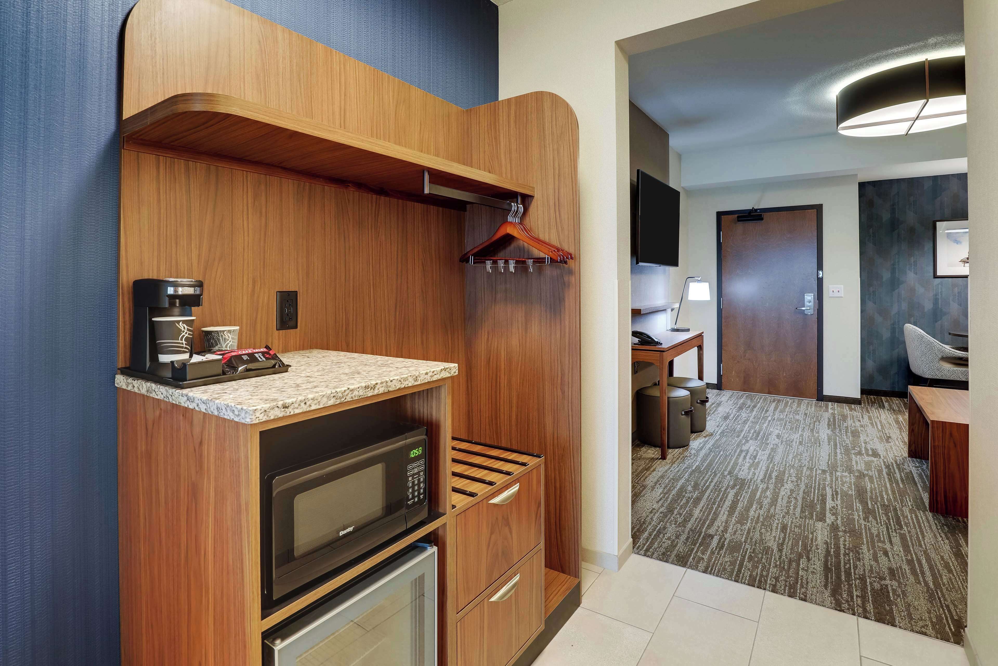 A compact kitchen with a microwave, coffee maker, and a wooden cabinet.
