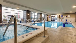 Una piscina interior con agua cristalina, escaleras de metal y peldaños con azulejos.