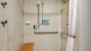 A shower area with a bench, grab bars, and a handheld showerhead.
