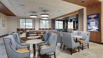 A modern restaurant with a bar area, seating arrangements, and a view of the kitchen.