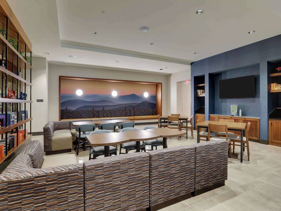 A modern lounge area with a large wall mural, seating arrangements, and a flat-screen TV.