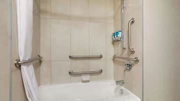 A bathroom with a bathtub, grab bars, and a showerhead.