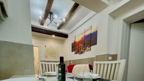 A dining area with a glass table, white plates, cutlery, and a bottle of olive oil. - 50 Tourist House Bologna Pratello Garden (Bologna)