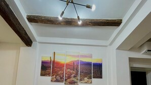 A red sofa with a white blanket, a ceiling light fixture, and a wall-mounted painting of a desert landscape. - 50 Tourist House Bologna Pratello Garden (Bologna)
