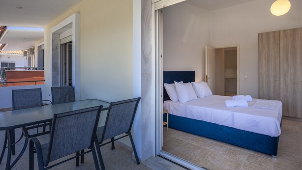 Una camera d'albergo con un letto, un tavolino con sedie e vista sul balcone.