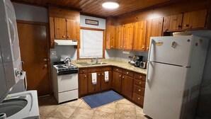 A compact kitchen with wooden cabinets, a white stove, a sink, and a refrigerator. - Beachside Retreat (North Myrtle Beach)