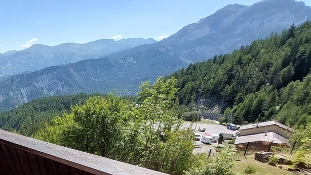 Vista sulle montagne, un'area di parcheggio e un edificio con tetto spiovente.