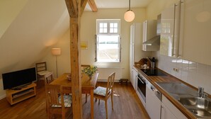Una cocina con vigas de madera, un comedor con mesa y sillas, un televisor y una ventana con vistas.
