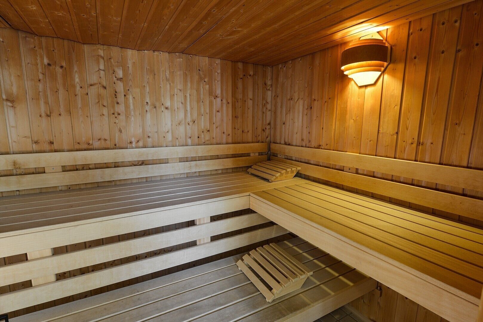 Una sauna de madera con bancos y una lámpara fijada a la pared.
