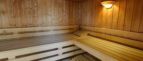 Una sauna de madera con bancos y una lámpara fijada a la pared.