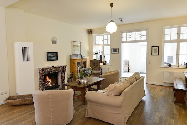 A living room with a fireplace, a sofa, a dining table, and a chandelier.