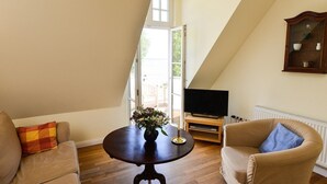 Un salon avec un téléviseur, une table ornée d’un vase et deux canapés.