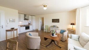 A spacious living area with a kitchen, a dining table, and a sofa. - Holiday Apartment "Gut Grubnow Rügen - 1" with Lake View, Shared Garden & Wi-Fi (Neuenkirchen)