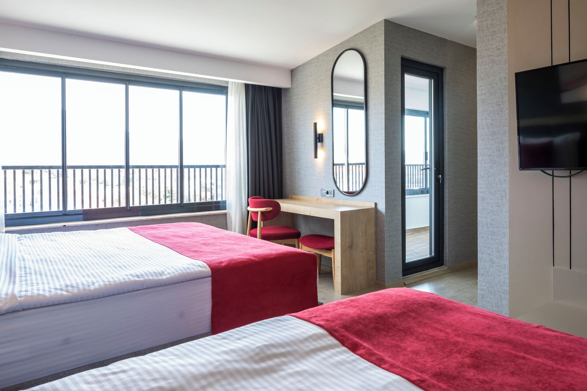 Une chambre d’hôtel avec deux lits, un bureau, un miroir et une télévision.