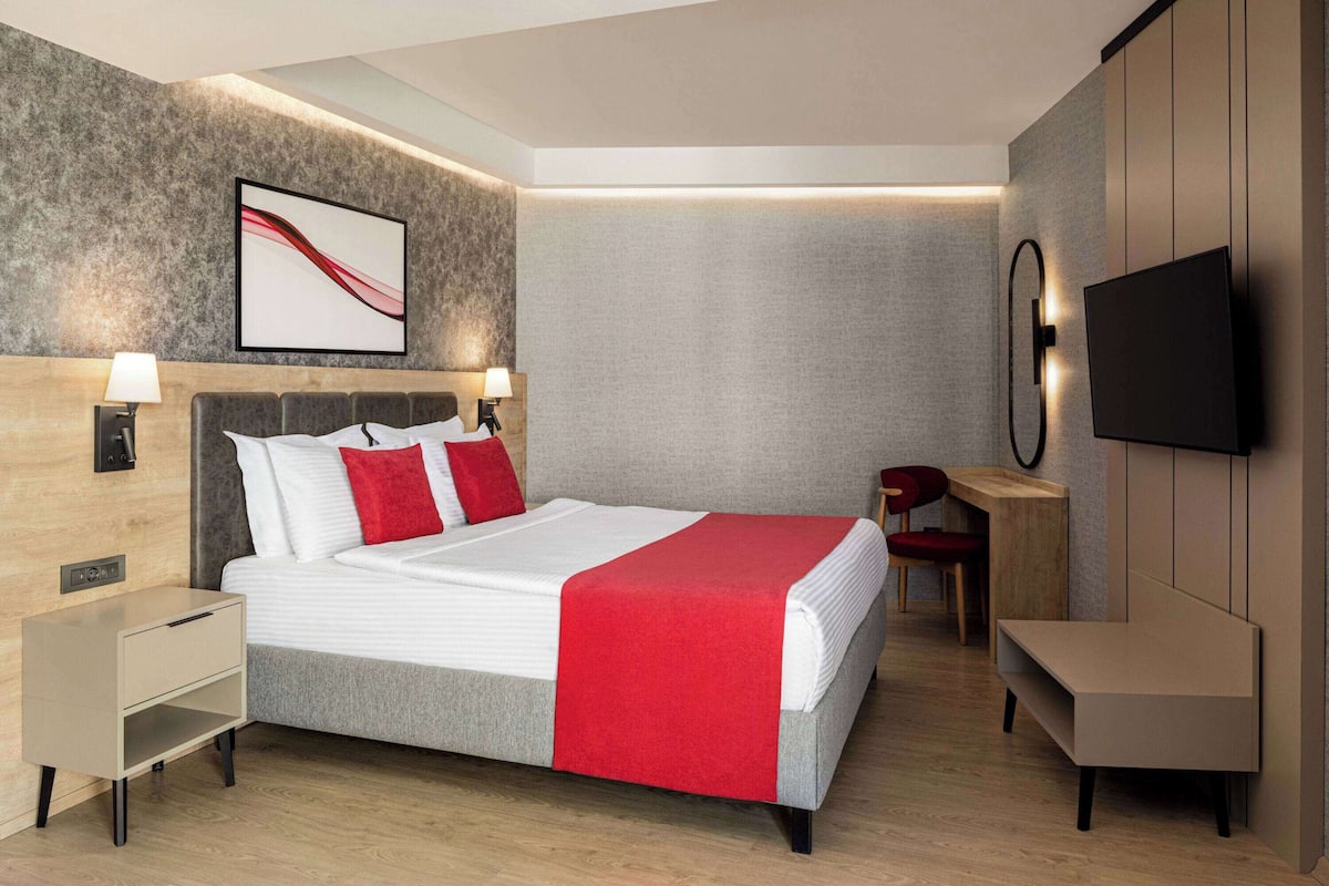 Een moderne hotelkamer met een groot bed, nachtkastjes, een bureau en een televisie.
