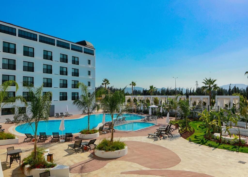 A hotel with a large pool area, multiple lounge chairs, and a building with numerous windows.