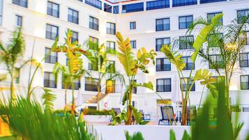 A multi-story hotel with balconies, surrounded by lush greenery.