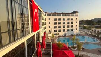 Un hotel con zona de piscina, sombrillas rojas y una bandera.