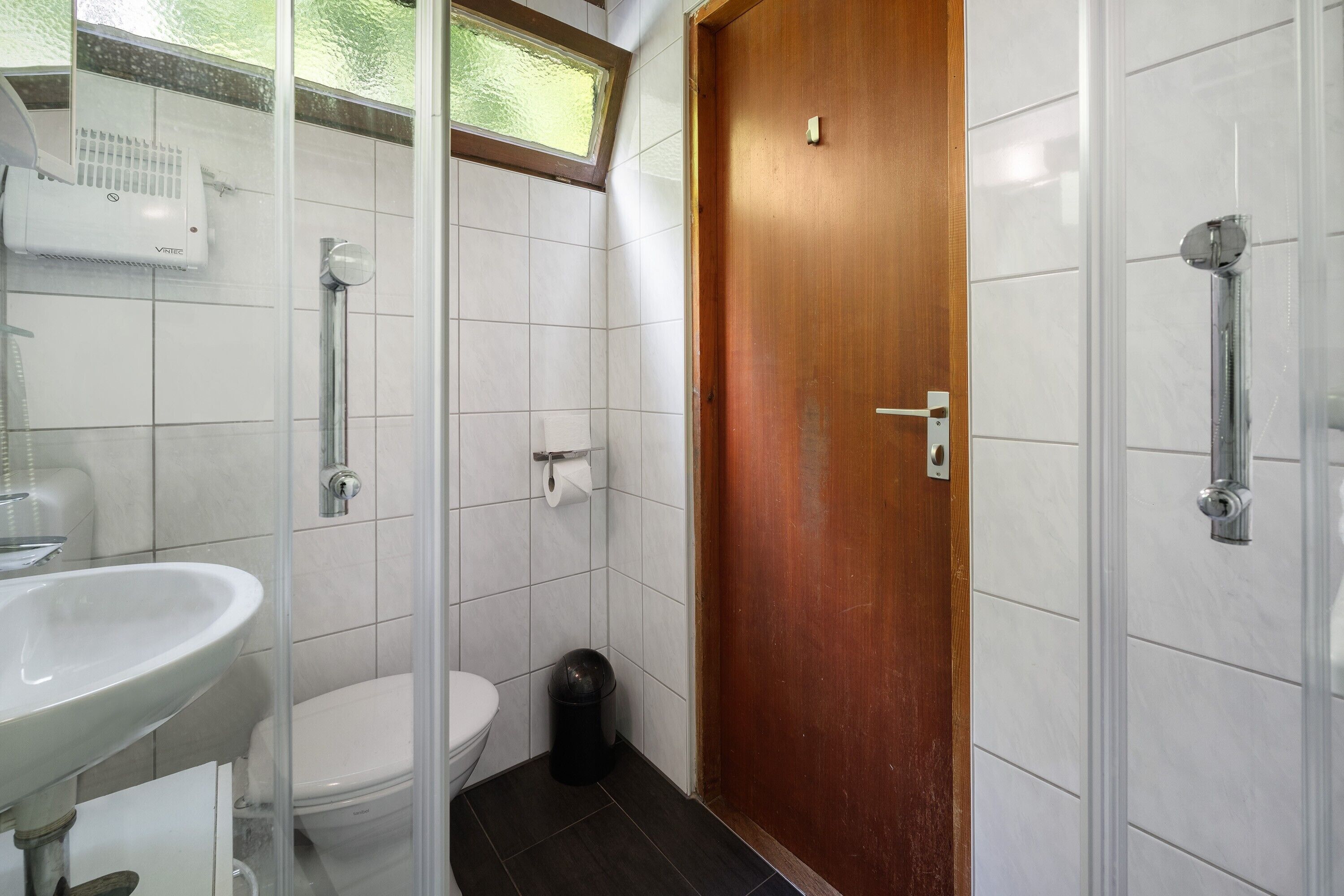 A bathroom with a white sink, toilet, and shower.